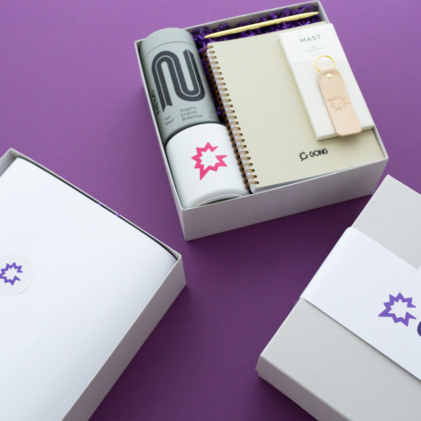 staggered gift boxes with gong branded products on purple background