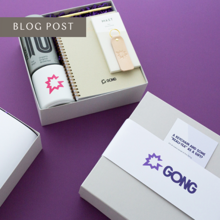two staggered gift boxes with gong branded products on purple background